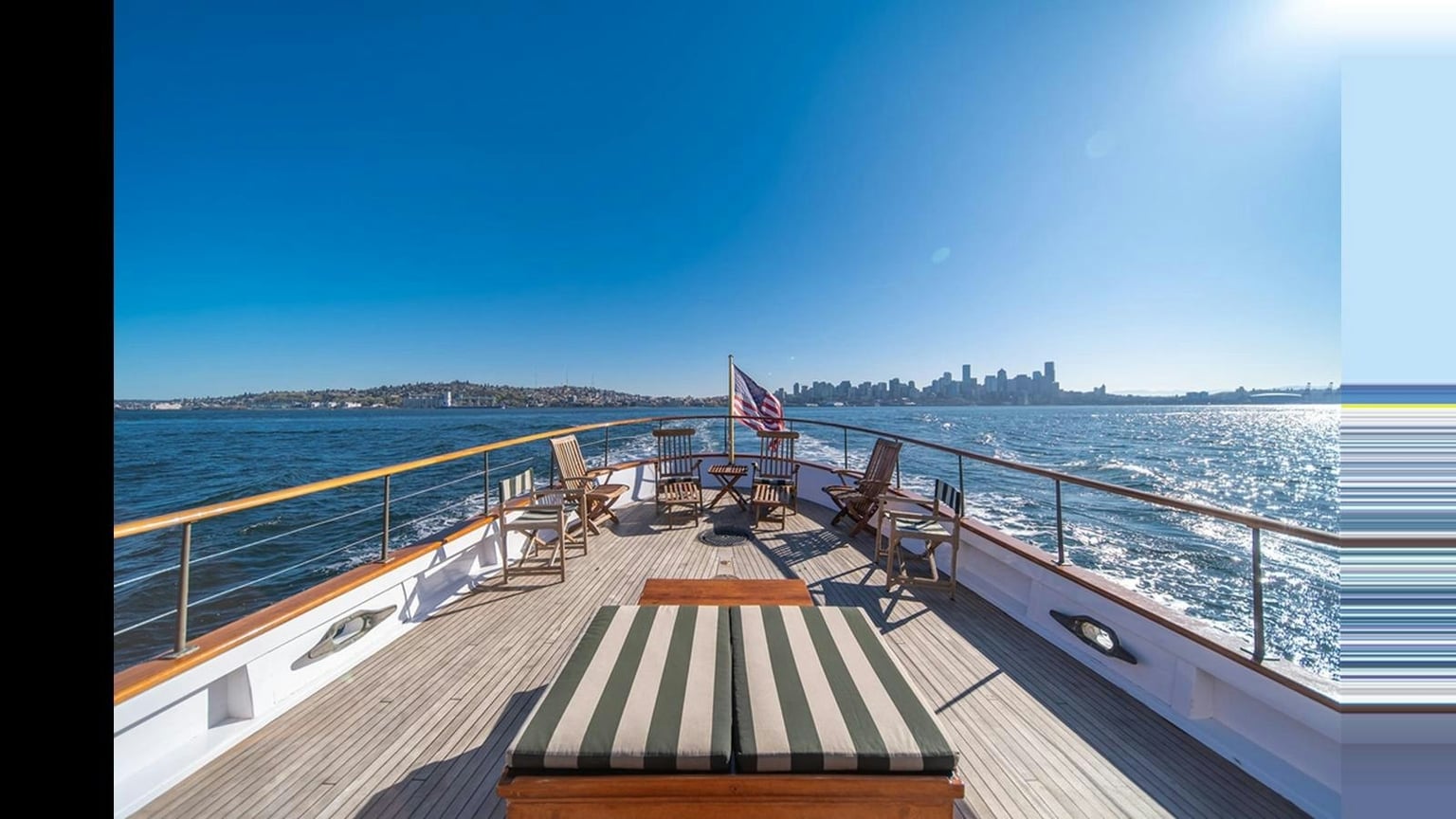 Teak chairs and varnished rails on Blue Peter’s aft deck, with Seattle beyond